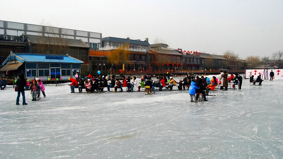 Shichahai, Beijing has groups of people sledging over the frozen lake.