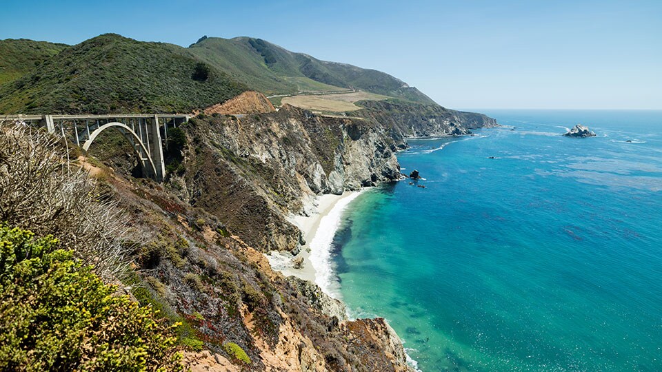 Bixby Bridge on a perfect summer day, Pacific Coast Highway Route 1, California. Beautiful bay full of clear blue water and famous landmark Bixby Bridge.